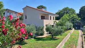 A two-story house with a red-tiled roof, surrounded by greenery and a clear blue sky. - Apartment Dunato I - with sea view, 310 m from the sea, balcony, air conditioning, BBQ (Šilo)