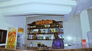 Un coin bar avec une variété de bouteilles d’alcool exposées sur des étagères, un réfrigérateur orné d’une publicité pour une boisson, et un panneau indiquant un prix de 150,46 $.