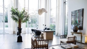 A modern office space with a large window, a reception desk, and a potted plant. - Enjoy Space and Comfort in 2BE in Las Condes (Santiago)