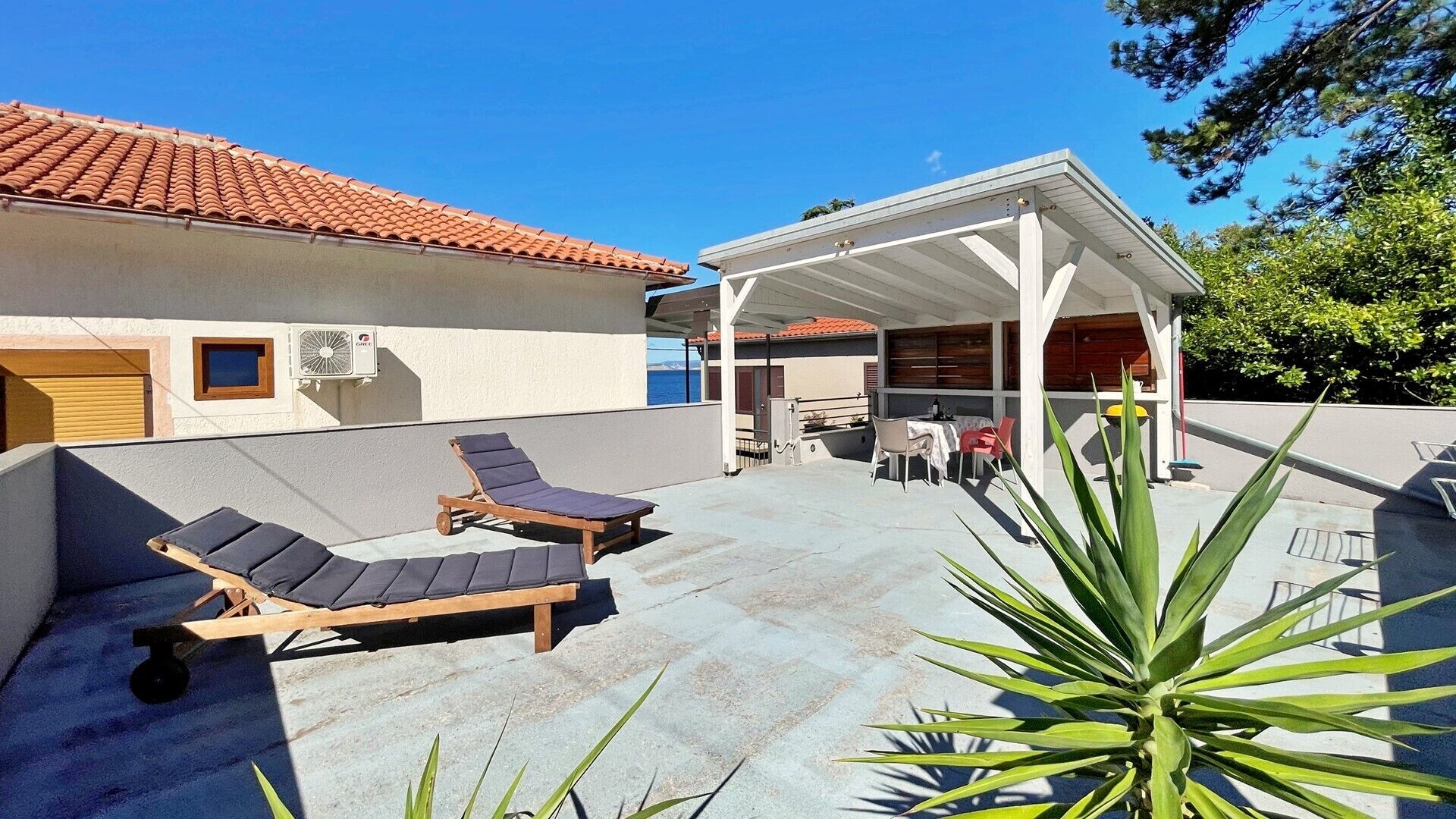 A covered outdoor area with two lounge chairs, a table, and chairs.