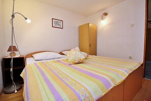A bedroom with a bed, a bedside lamp, a wardrobe, and a wall-mounted light fixture.