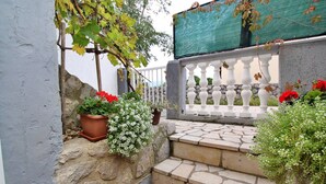 Una escalera de piedra que conduce a un balcón blanco con flores rojas y plantas en macetas.