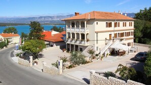 A two-story building with a balcony, a stone wall, and a view of the sea. - Apartment Ivanka - 200 m from sea, close to beach, private parking, terrace (Soline)