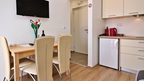 Une cuisine compacte avec un coin repas, un téléviseur à écran plat et un petit réfrigérateur.