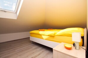 Quarto pequeno com uma cama de solteiro, teto inclinado e claraboia.