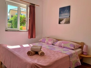 Una camera da letto con un letto, una finestra con tende, una lampada da comodino e un quadro appeso al muro.