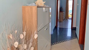Een gang met een houten kast, een koelkast en een decoratieve plant.