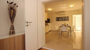 Une cuisine moderne avec des meubles blancs, un coin repas comprenant une table et des chaises, et un espace de vie avec un canapé.