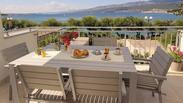Une table dressée avec des aliments pour le petit-déjeuner, offrant une vue sur la mer.