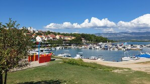 A marina with boats docked, a clear sky, and buildings in the background.