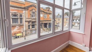 A room with large windows offering a view of a street with buildings and a fire station.