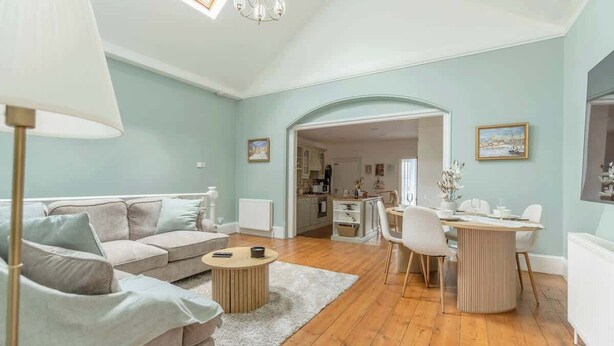 A living room with a sofa, coffee table, and dining area with chairs and a table.
