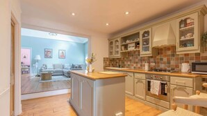 A modern kitchen with a central island, built-in cabinets, and a dining area with a sofa and table.