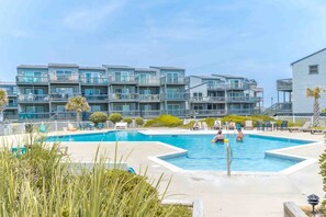 A swimming pool with a poolside area, surrounded by a multi-story residential building with balconies. - A Little Slice of Paradise on North Topsail Beach - 2BR Shipwatch Condo (North Topsail Beach)