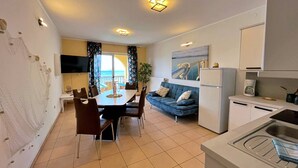 A modern apartment with a dining area, a sofa, a kitchen, and a balcony with a view. - Apartment Neptun - seafront, 20 m from sea, sea view, terrace, private parking (Šilo)