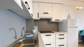 A compact kitchen with white cabinets, a stainless steel sink, and a built-in refrigerator. - Apartment Neptun - seafront, 20 m from sea, sea view, terrace, private parking (Šilo)