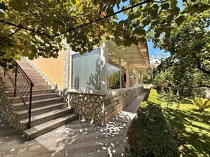 Ein Haus mit Steinstufen, einer Veranda und einem gepflegten Garten.