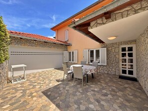 A patio with stone flooring, a table with chairs, and a covered area with a door. - Apartment Nevenka - 70 m from the sea, terrace, town center, barbecue (Cizici)