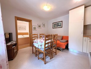 Quarto compacto com cama, mesa de jantar com cadeiras, sofá e cozinha compacta.