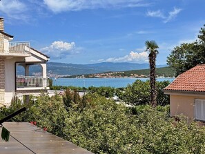 Un edificio residenziale con un balcone che si affaccia su un corso d'acqua e delle colline.