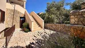 A modern building with a stone facade, a staircase leading to a door, and a stone wall with plants.
