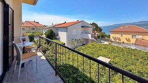 A balcony with a table and chairs, a view of neighboring houses, and a clear sky.