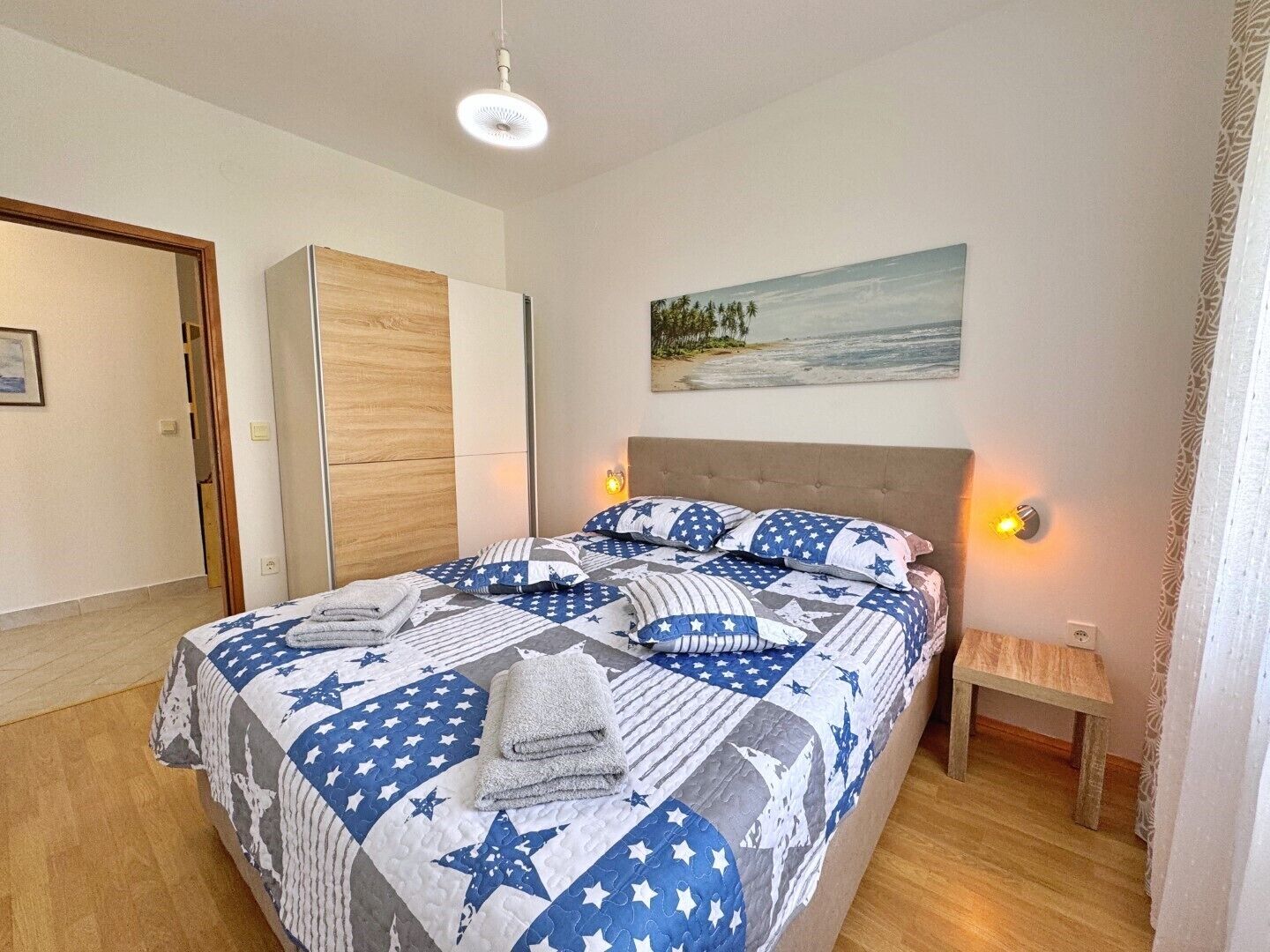 A bedroom with a bed, a nightstand, a painting, and a door.