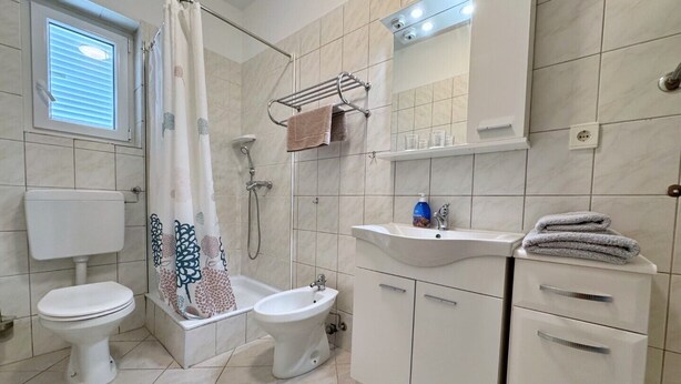 A modern bathroom with two toilets, a shower, a sink, and a mirror. - Apartment Nikolic - balcony, quiet area, garden, supermarket (Šilo)