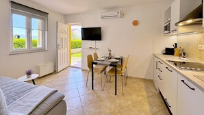 Un espace de vie compact comprenant un coin repas, une kitchenette et un lit.