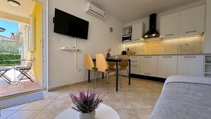 Une cuisine moderne avec des meubles blancs, un téléviseur à écran plat et un coin repas équipé de deux chaises.
