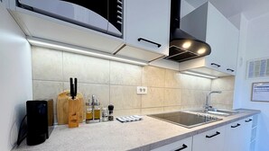 Une cuisine moderne avec des armoires blanches, un comptoir en granit, un four encastré et un évier en acier inoxydable.