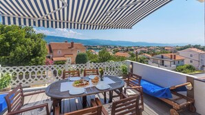 A terrace with a table set for dining, overlooking a scenic view of houses and mountains. - Apartment Presker - sea view, modern, 280 m from sea, private terrace, BBQ (Šilo)