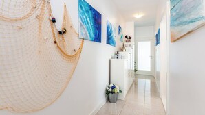 A hallway with a net decoration, a refrigerator, and multiple blue paintings on the walls. - Apartment Presker - sea view, modern, 280 m from sea, private terrace, BBQ (Šilo)