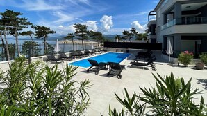 Zona de piscina en la azotea con sillones y vista al mar.