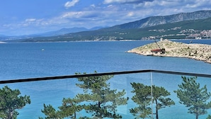 A coastal view with a clear sky, a body of water, and a distant mountain range.
