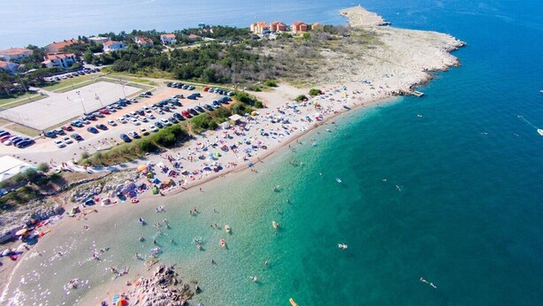 Vista aérea de una zona costera con playa, estacionamiento y edificios.