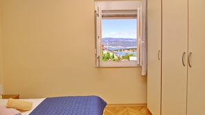 Ein Schlafzimmer mit einem Bett, einem Fenster mit Blick auf die Stadt und einem Kleiderschrank.
