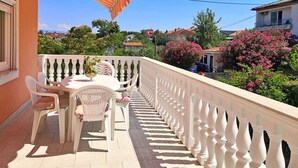 Ein Balkon mit weißen Geländern, einem Tisch und Stühlen.