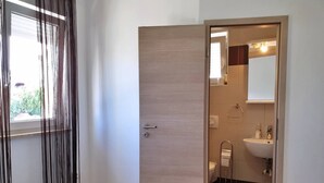 A bedroom with a bed, a wooden door, and a window with curtains. - Apartment Rea - 220 m from sea, pet-friendly, private parking, terrace (Šilo)
