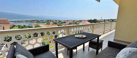 Ein Balkon mit Tisch und Sitzgelegenheiten, der einen schönen Blick auf einen See und ferne Berge bietet.