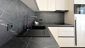 A modern kitchen with a black marble backsplash, a black sink, and white cabinetry. - Apartment Scheich - seafront, 20 m from sea, ground floor, terrace (Šilo)
