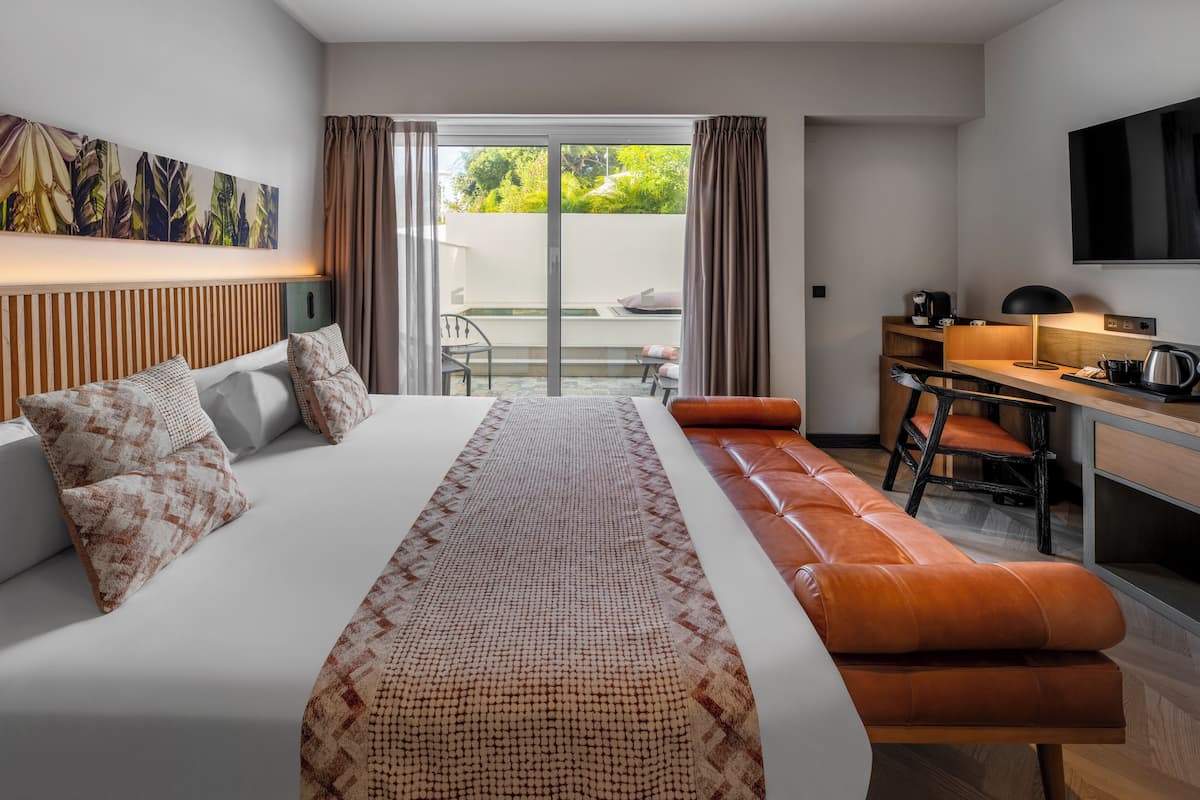 Ein modernes Hotelzimmer mit einem großen Bett, einem Schreibtisch und Blick ins Freie.
