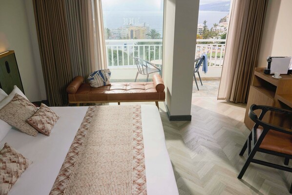 Une chambre d’hôtel avec un lit, un canapé, une chaise, un bureau et un balcon avec vue.
