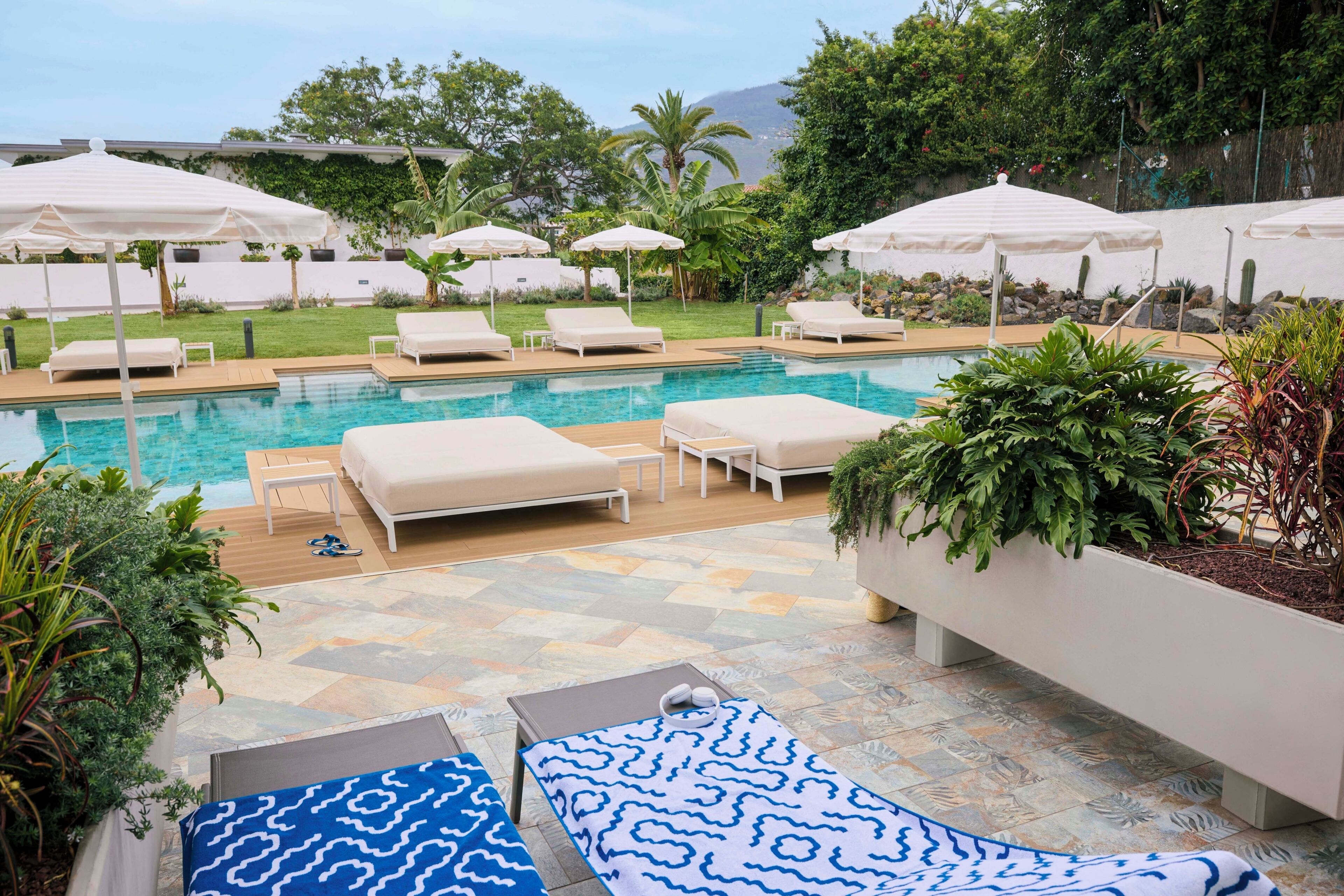 A poolside area with lounge chairs, umbrellas, and a pool.