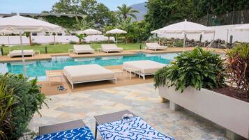 A poolside area with lounge chairs, umbrellas, and a pool.
