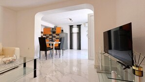 Een moderne woonkamer met een glazen salontafel, een flatscreen televisie en een minimalistisch ontwerp.