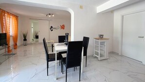Een moderne eetruimte met een witte tafel, zwarte stoelen en een glazen scheidingswand.