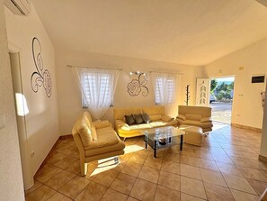 Un salon comprenant un ensemble de canapés, une table basse en verre et une porte donnant sur l’ext érieur.