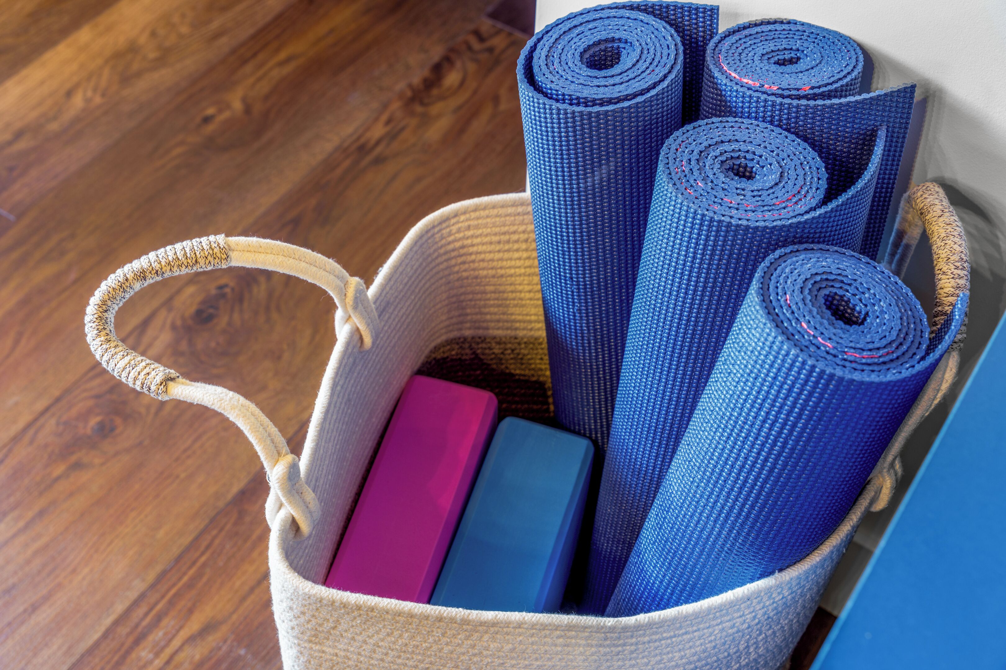 A woven basket containing yoga mats and a couple of books.