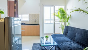 A modern living room with a glass coffee table, a dark sofa, and a kitchen in the background. - Housr Benson Marathahalli Bangalore (Bengaluru)